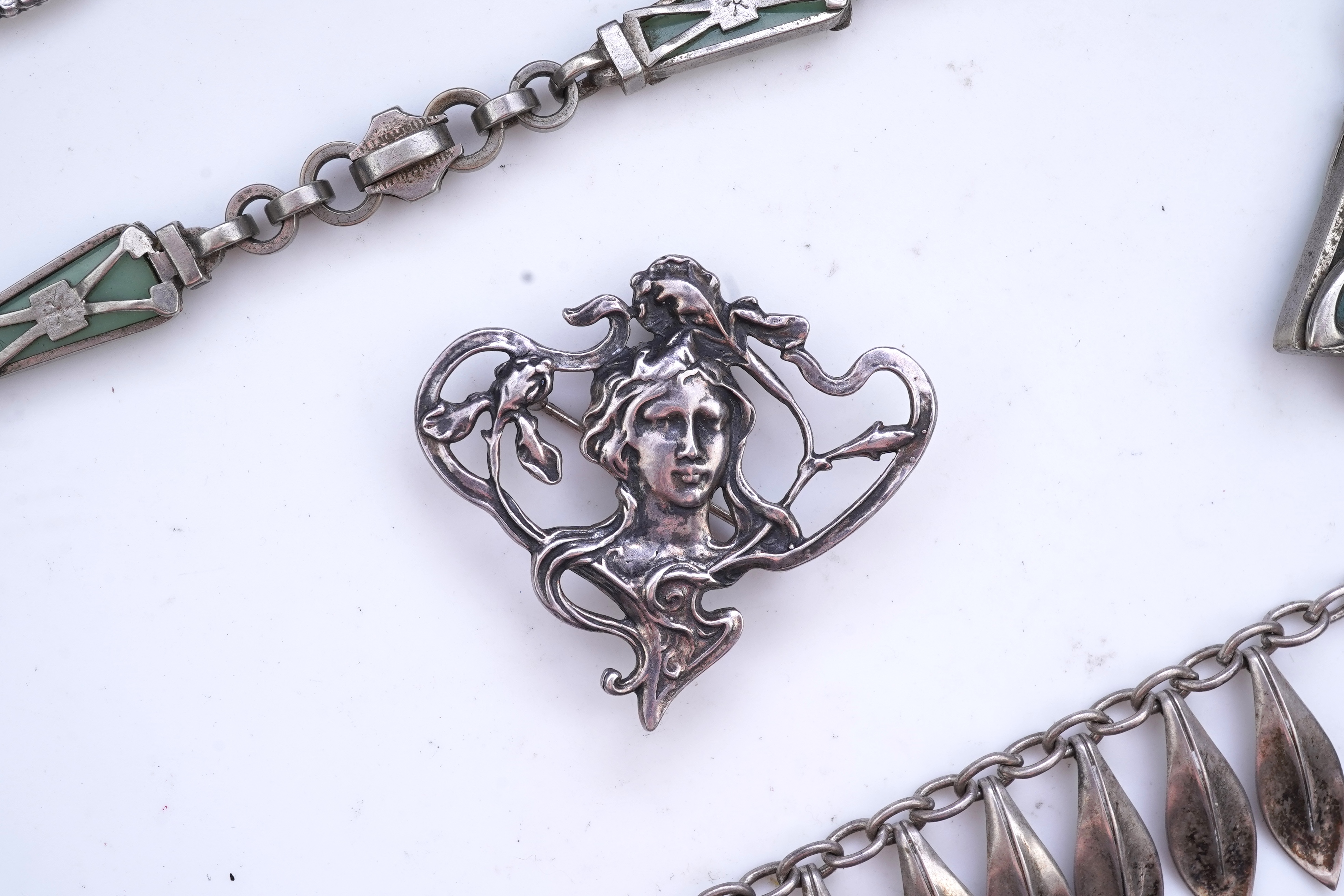 A collection of three silver chains and an Art Nouveau brooch, early 20th century